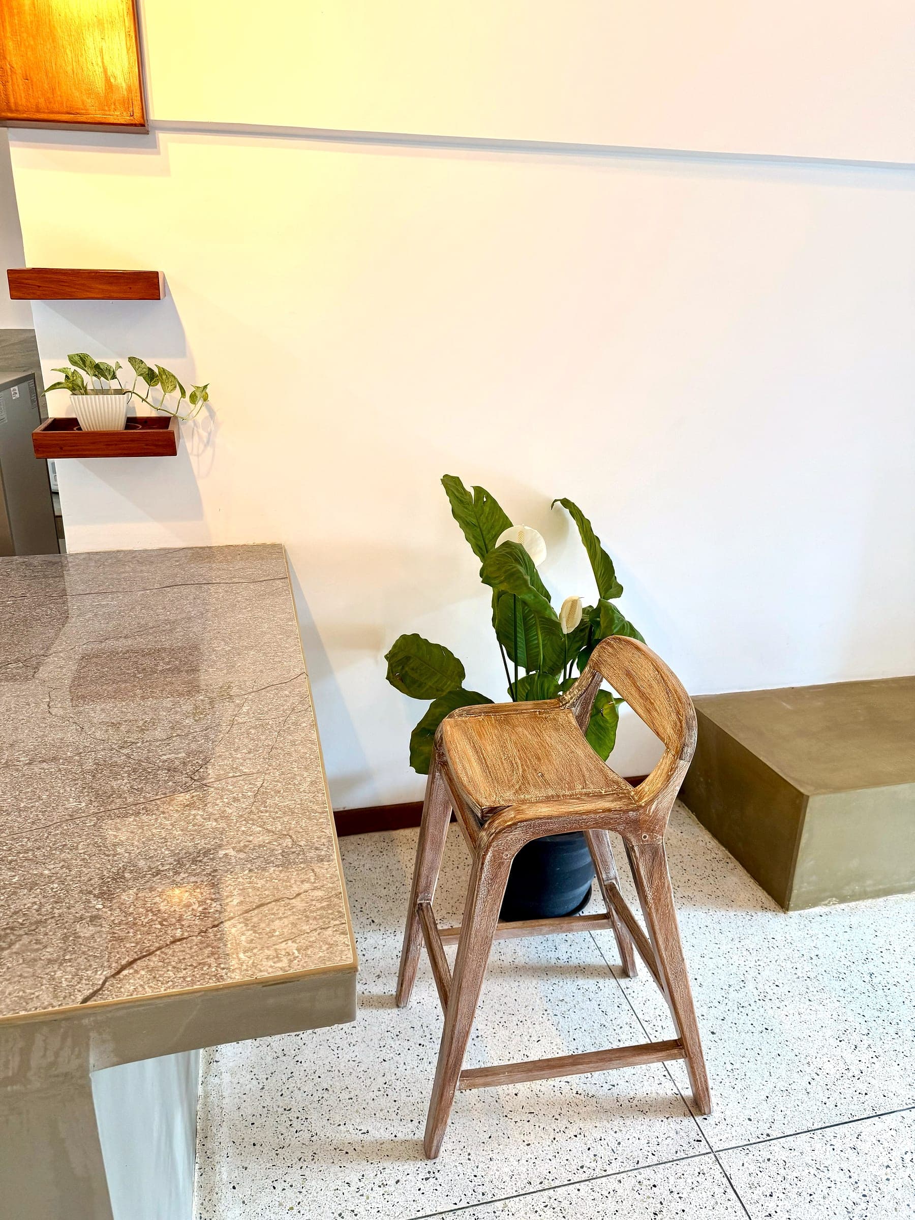 Stone kitchen counter with a wooden bar stool and a potted plant